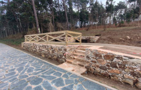 acceso cerrado por obras al mirador con suelo de piedra y paisaje boscoso