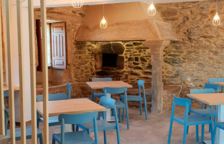 zona de comedor con varis mesas y sillas y un horno de piedra al fondo