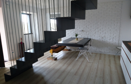 vista desde el lateral de las escaleras de acceso al piso superior, se puede ver también una mesa grande de comedor