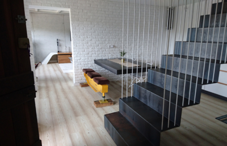 escaleras de subida al piso superior y se ve una mesa en color negro grande de comedor