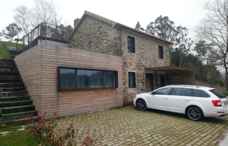vista completa de una vivienda con fachada en piedra y un coche aparado en la entrada