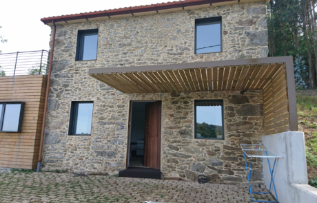 fachada en piedra de una vivienda, la puerta de madera está entreabierta