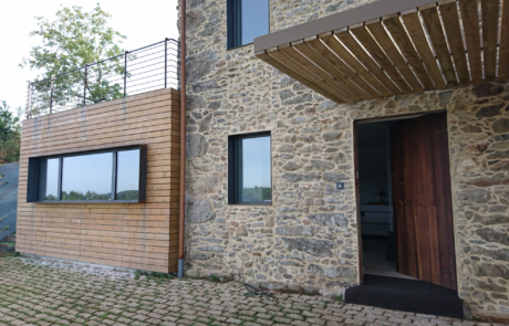 fachada en piedra de una vivienda, la puerta de madera está entreabierta
