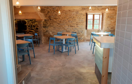 zona de comedor con varias mesas y sillas al fondo un horno de piedra