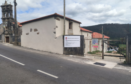 fachada exterior de un rectoral en medio de una carretera y una vivienda al lado, el cielo está muy nuboso