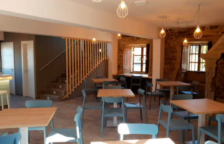 mostrador y zona de servir comidas, se ven las escaleras para subir a la zona superior y varias mesas