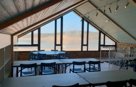 zona de comedor con vistas a un lago, hay varias mesas y sillas