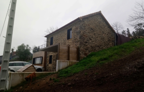 fachad exterior en piedra de una vivienda, se ve un coche aparcado en la entrada
