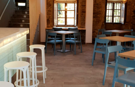 mostrador y zona de servir comidas, se ven las escaleras para subir a la zona superior y varias mesas