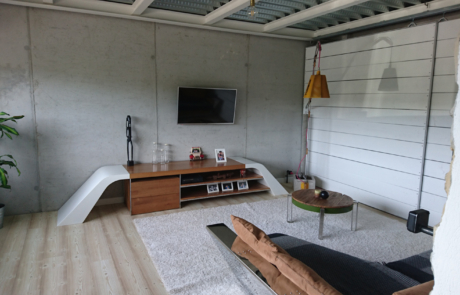 salón de una vivienda con pared se ve una pequeña estantería y la televisión colgada en la pared