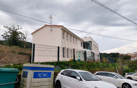 vista de una casa encima de un montículo, debajo coches aparcados