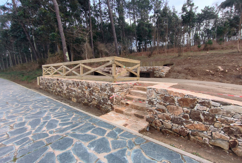 acceso cerrado por obras al mirador con suelo de piedra y paisaje boscoso
